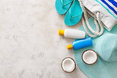 Beyaz arka planda güneş kremi ve aksesuarlı plaj çantası.