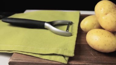 Çiğ patates, soyucu ve yemek masada.