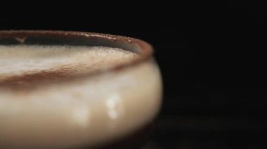 Siyah arka planda dönen bir bardak espresso martini kokteyli, yakın plan.