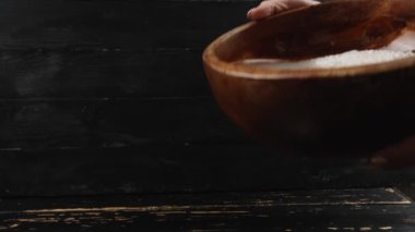 Koyu ahşap arka planda kaseden pirinç suyu dökülüyor.