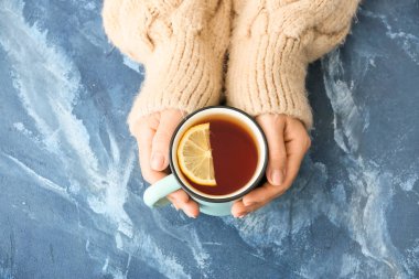 Masasında bir fincan sıcak çay olan kadın.