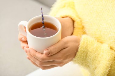 Evde bir fincan sıcak çay içen kadın, yakın plan.