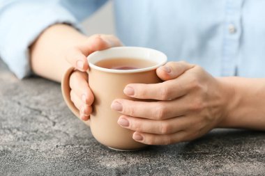 Masada bir fincan sıcak çay içen kadın, yakın plan.
