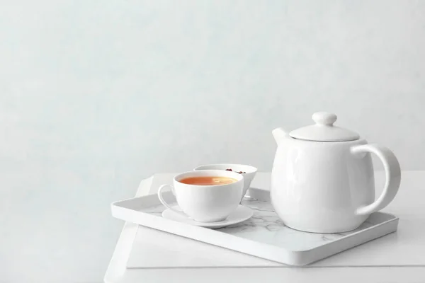 Cup of hot beverage, teapot and jam on table