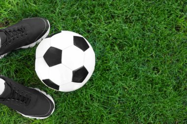 Yeşil çimlerin üzerinde futbol topu olan bir futbolcu.