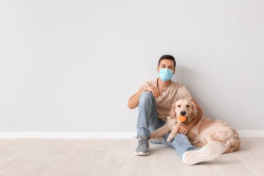 Koruyucu maskeli genç bir adam ve sevimli bir köpek.