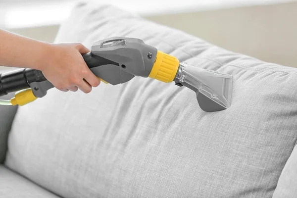 Dry cleaner\'s employee removing dirt from sofa in house