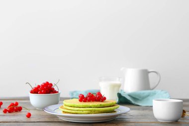 Lezzetli yeşil krep ve ahşap masada böğürtlen tabağı.