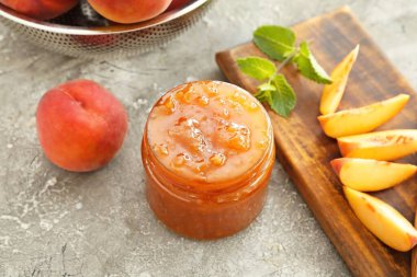 Arkaplanda bir kavanoz şeftali reçeli.