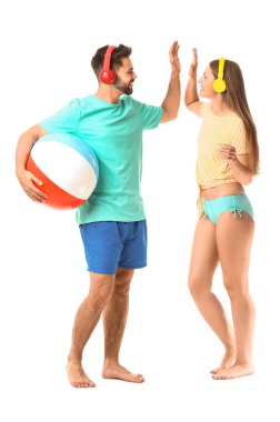 Kulaklıklı ve şişme toplu genç çift beyaz arka planda birbirlerine beşlik çakıyor.