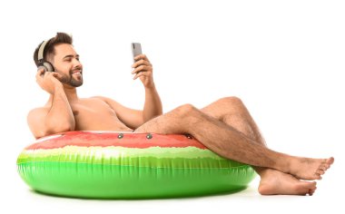 Kulaklıklı genç adam, beyaz arka planda şişirilebilir yüzük ve cep telefonu.