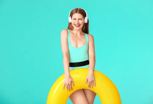 Junge Frau Mit Kopfhörer Und Aufblasbarem Ring Auf Farbigem Hintergrund — Stockfoto