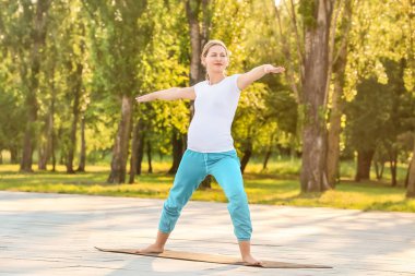 Genç hamile kadın dışarıda yoga yapıyor.