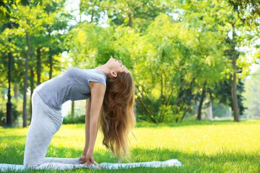 Genç hamile kadın dışarıda yoga yapıyor.