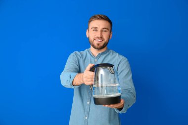 Arka planda elektrikli su ısıtıcısı olan genç adam.