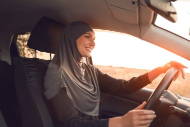Genç Müslüman kadın arabada oturuyor.