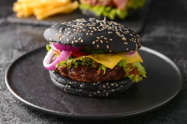 Tabağında siyah çörek olan lezzetli bir hamburger.