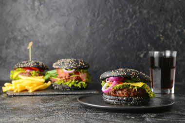 Esmer arka planda siyah çörekli lezzetli bir hamburger.