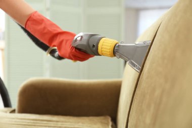 Kuru temizlemecinin çalışanı evdeki kanepedeki kiri temizliyor.