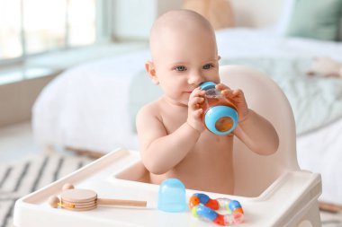 Sevimli küçük bebek evde biberondan meyve suyu içiyor.