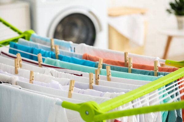 Clean clothes hanging on dryer in laundry room, closeup