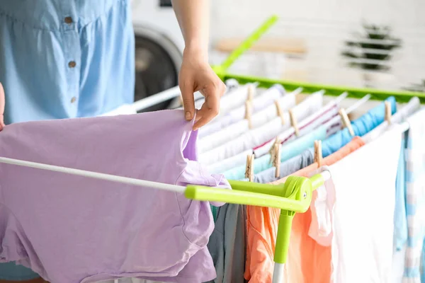 Woman hanging clean clothes on dryer in laundry room, closeup