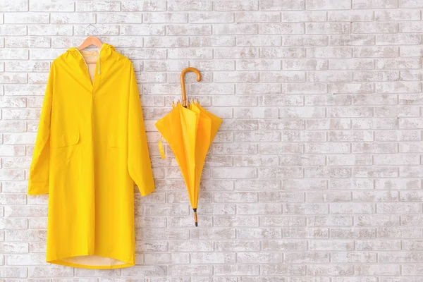 Tuğla arka planda yağmurluk ve şemsiye