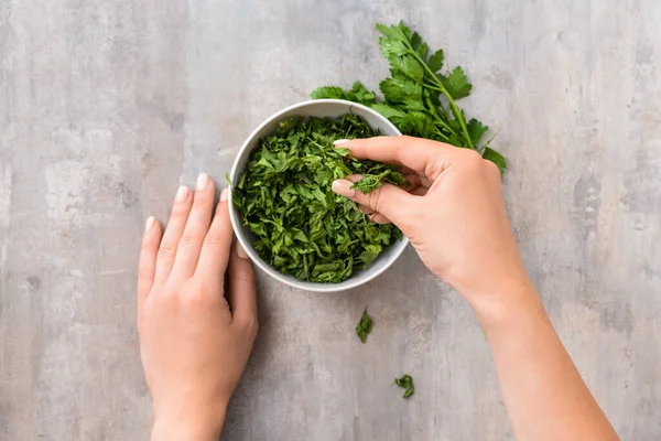 Gri arka planda kuru maydanozlu kadın elleri