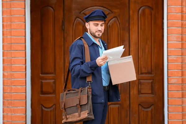 年轻英俊的邮递员 在户外带着包裹和信件 — 图库照片