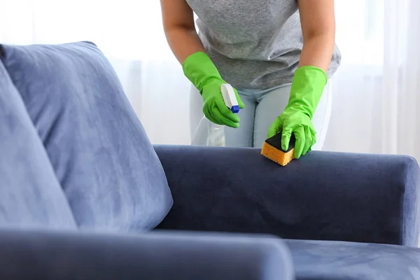 Woman removing dirt from sofa at home