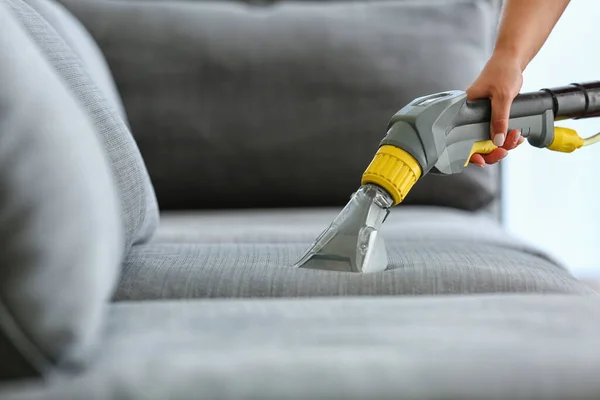 Dry cleaner\'s employee removing dirt from sofa in house