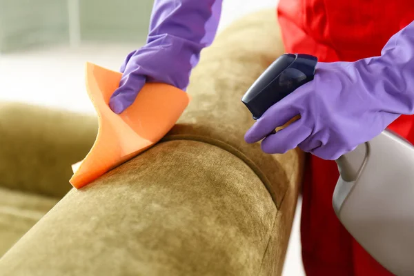 Dry cleaner\'s employee removing dirt from sofa in house