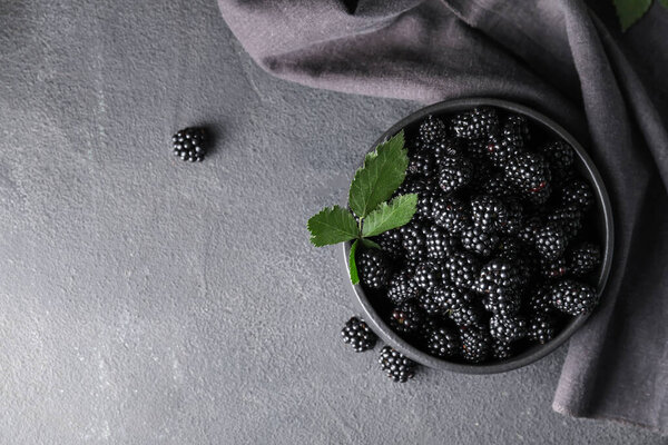 Bowl with tasty blackberry on dark background