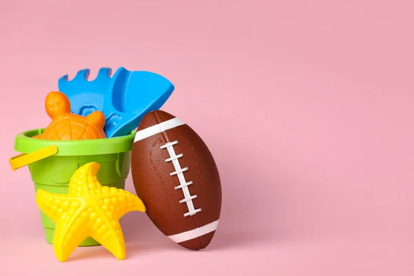 Rugby ball with kid toys on color background