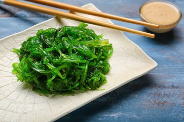 Plate with tasty seaweed salad on table clipart