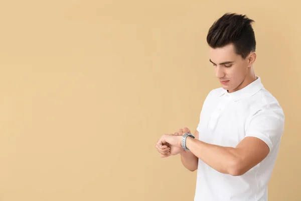 Handsome Man Stylish Hairdo Looking His Watch Color Background — Stock Photo, Image