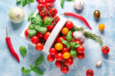 Taze kiraz domatesli sepet, sebzeler ve baharatlar masada.