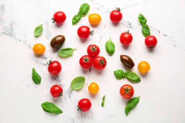 Taze vişneli domates ve açık arkaplanda fesleğen.