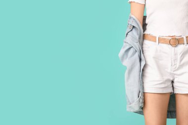 Kot pantolonlu güzel bir kadın. Arka planda renkli giysiler.