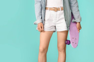 Kot pantolonlu güzel bir kadın. Arka planda renkli giysiler.