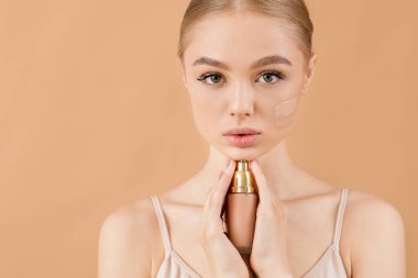 Yüzünde temeli olan güzel, genç bir kadın.