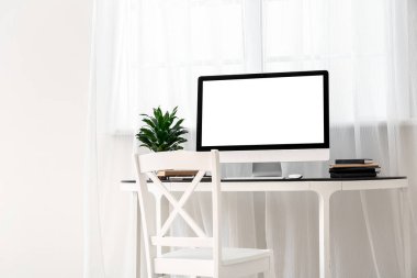 Pencerenin yanındaki masadaki modern PC monitörü