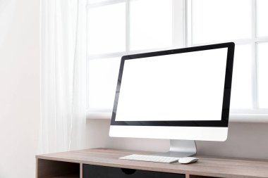 Pencerenin yanındaki masadaki modern PC monitörü