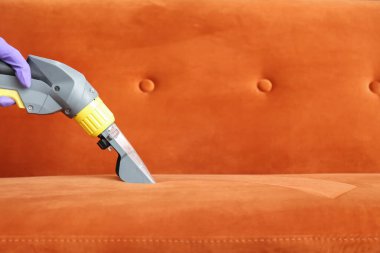 Kuru temizlemecinin çalışanı evdeki kanepedeki kiri temizliyor.