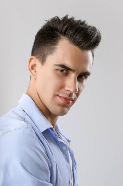 Açık arkaplanda şık saç stili olan yakışıklı adam.