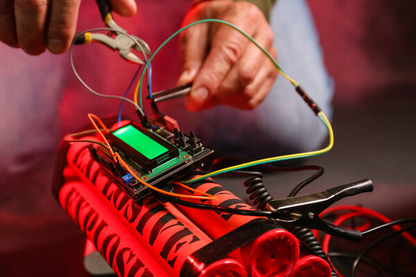 Человек обезвреживает бомбу за столом, крупным планом