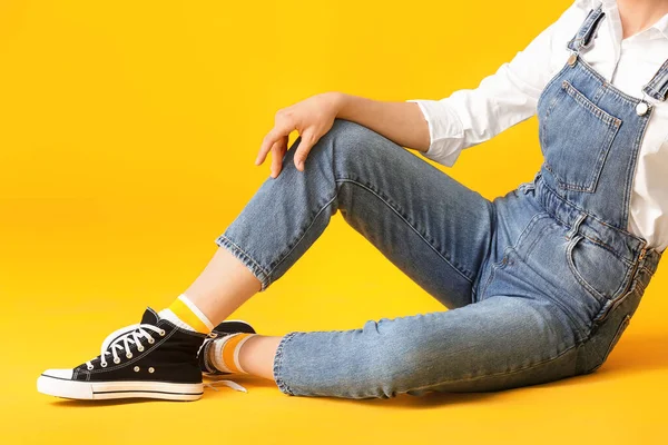 Kot pantolonlu güzel bir kadın. Arka planda renkli giysiler.