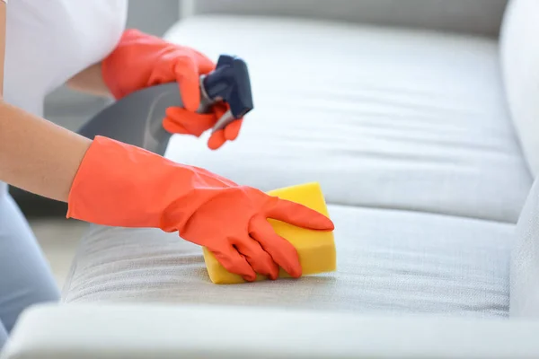 Woman removing dirt from sofa at home