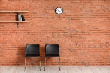 Odadaki tuğla duvarın yanında şık sandalyeler