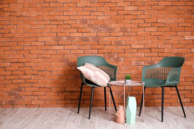 Şık koltuklar ve tuğla duvarın yanındaki masa.